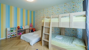 Ein Kinderzimmer mit Etagenbetten, einem Spielzeugregal und einer Wand mit Muster.