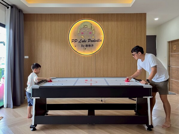 A foosball table in a room with wooden paneling and a sign reading "PP Lake Poolvilla By 春秋".