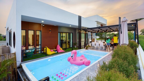 Ein modernes Haus mit Swimmingpool, Außenbereich mit Sitzgelegenheiten und einer überdachten Terrasse.