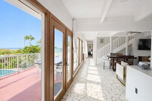 A spacious balcony with a pool, a staircase leading to an upper level, and a dining area with chairs and a table. - Central Oceanview Hawaii Style House Pool & SPA (Kailua-Kona)