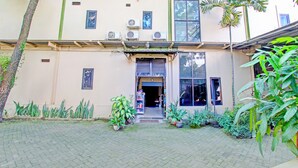 Een gebouw met een betegelde entree, airconditioners en potplanten.