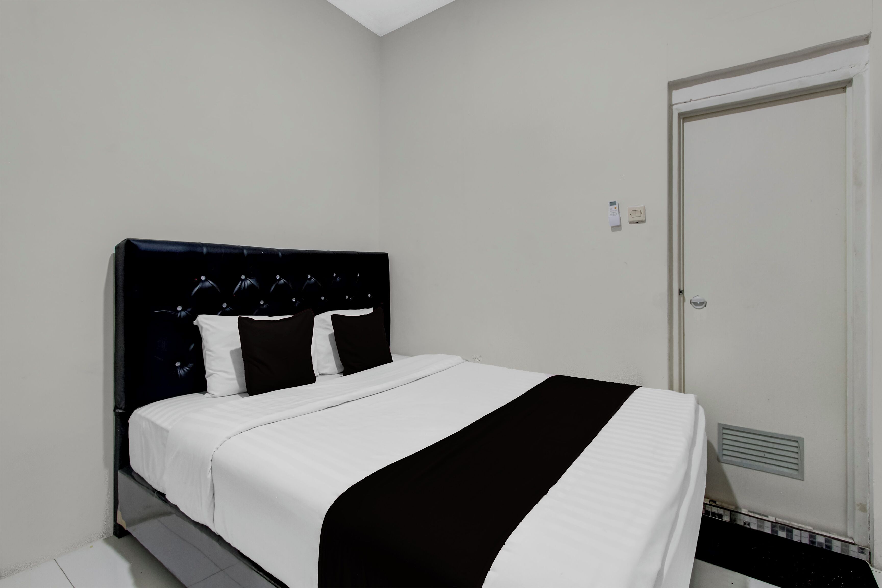 A neatly made bed with a black and white bedspread, a black headboard, and white pillows.