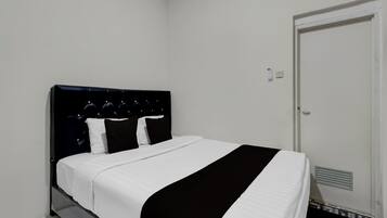 A neatly made bed with a black and white bedspread, a black headboard, and white pillows.