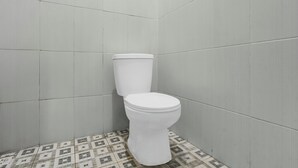 Een badkamer met toilet, betegelde wanden en een vloertegelpatroon.