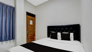 Een slaapkamer met een bed, een houten deur en een blauw gordijn.