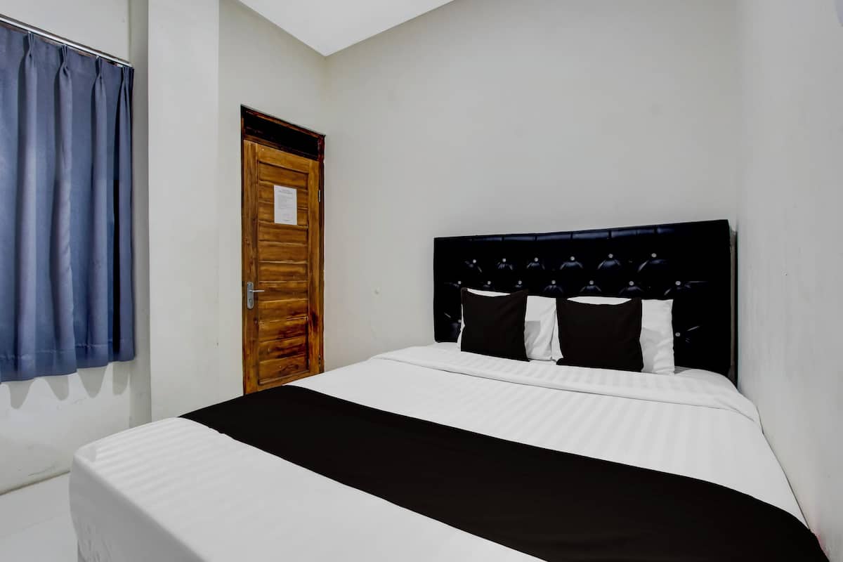 Een slaapkamer met een bed, een houten deur en een blauw gordijn.
