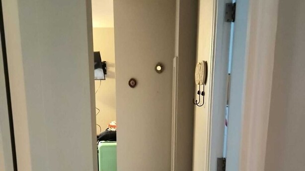 Een smalle gang met vloerbedekking die leidt naar een kamer met een groene stoel en een tafeltje.