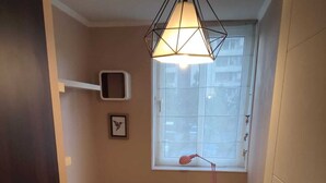 Een slaapkamer met een bed, nachtkastje met lamp, raam en deur.