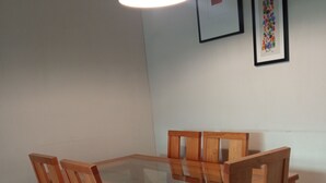 Een eetgedeelte met een houten tafel en stoelen, een hanglamp en kunstwerken in lijsten aan de muur.