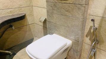 A bathroom with a white toilet, a shower, and a towel rack.