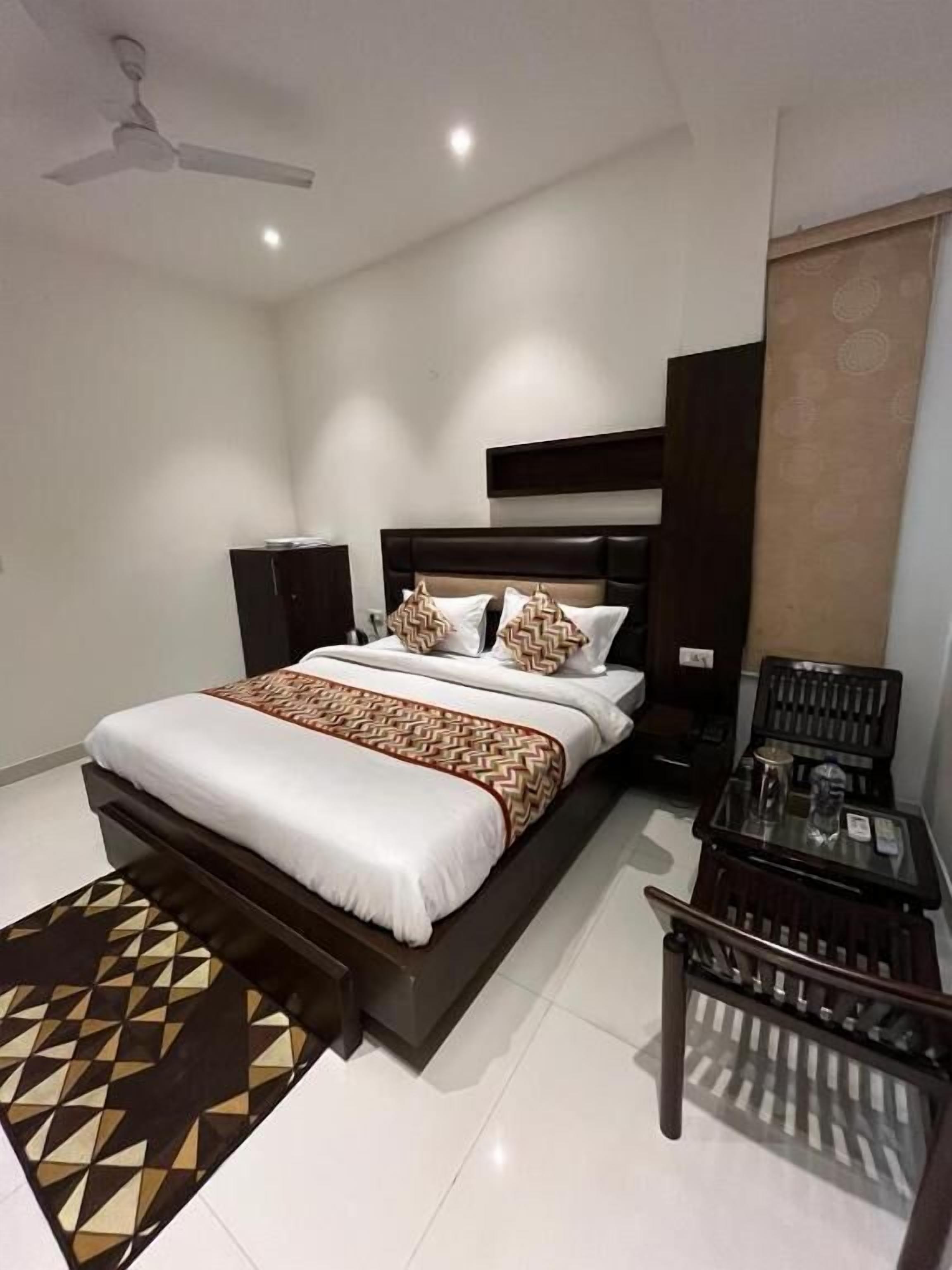 A modern bedroom with a bed, bedside tables, a chair, and a ceiling fan.