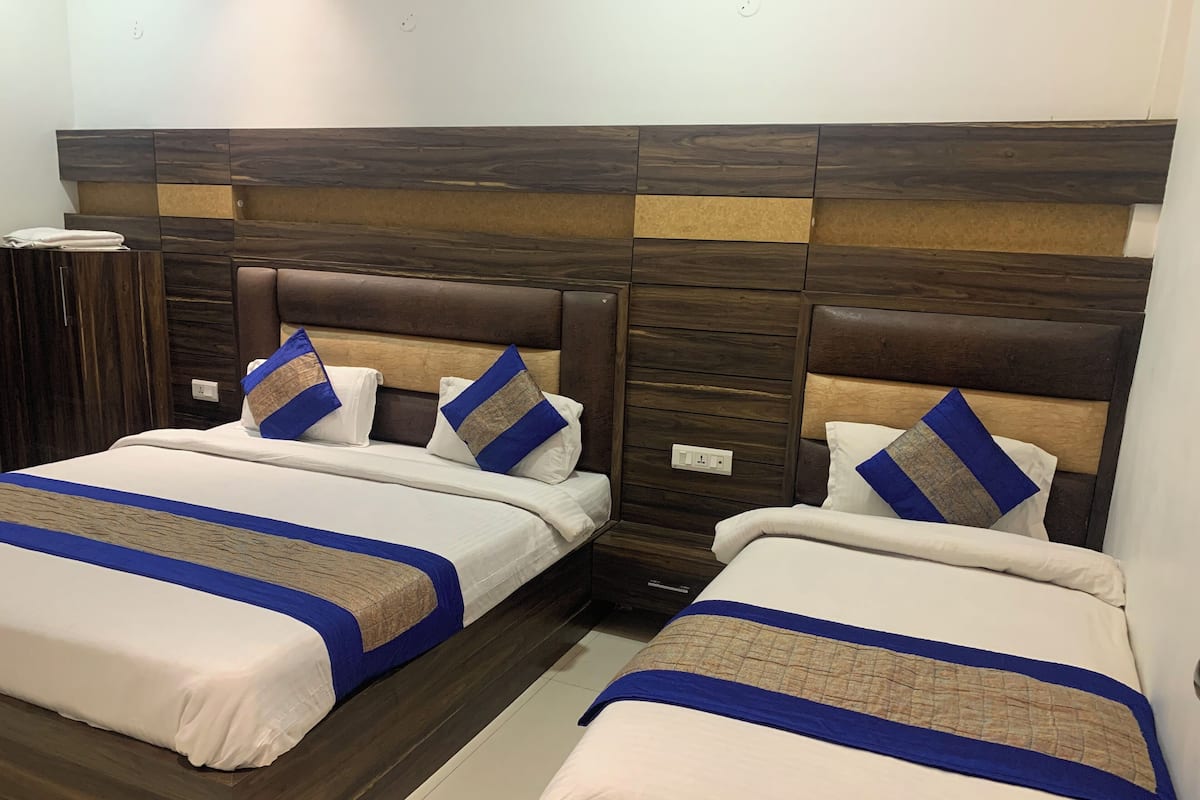 Une chambre d’hôtel avec deux lits, chacun doté d’une tête de lit en bois et d’une literie bleue et beige.