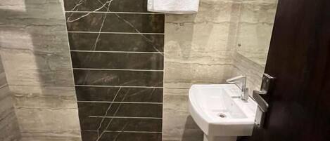Une salle de bain avec un lavabo, des carreaux de marbre foncé et une serviette accrochée au mur.