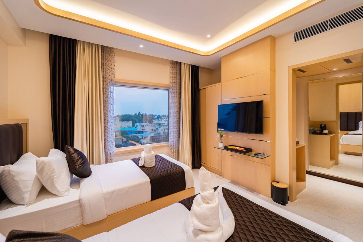 Habitación de hotel con cama, televisión, escritorio y ventana con vista a la ciudad.