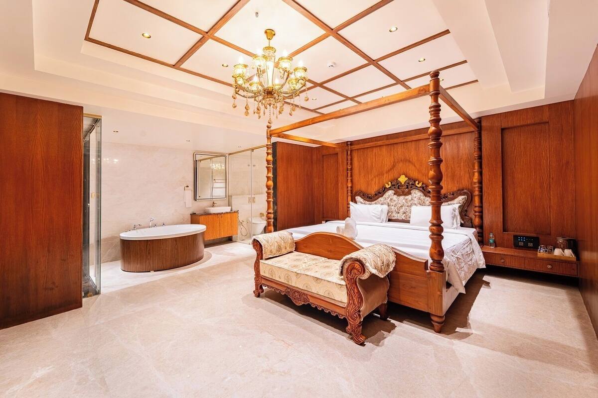 Una cama con dosel y cabecera de madera, una bañera redonda y un candelabro.