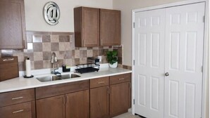 A kitchen with brown cabinets, a white door, and a welcome sign. - Payne Place 1 (Las Cruces)