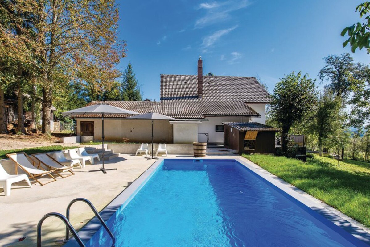 A swimming pool with lounge chairs and a small building with a tiled roof.