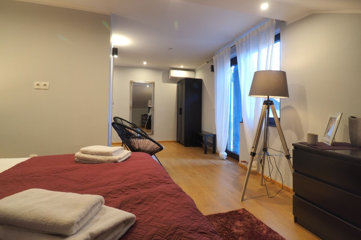 A bedroom with a large bed, a chair, a lamp, and a dresser.