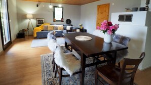 A cozy living room with a wooden ceiling, a dining table with chairs, a sofa, and a coffee table. - Apartments & Rooms Latin (Plaski)