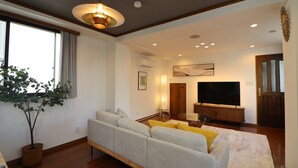 A modern living room with a sofa, a TV, and a large window. - Yokohama Mega Stay (Yokohama)