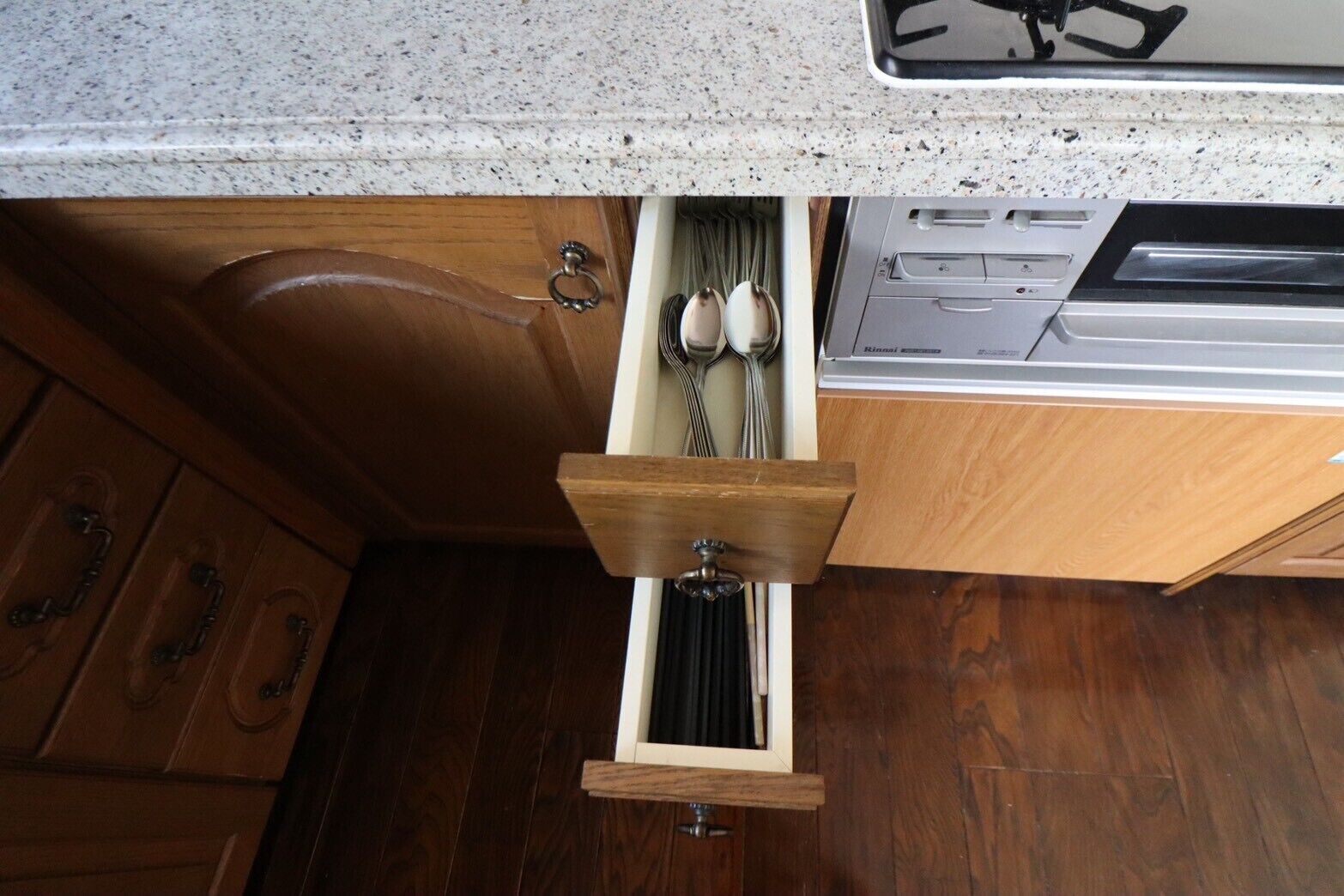 Una cocina con gabinetes de madera, encimera de granito y lavavajillas empotrado.