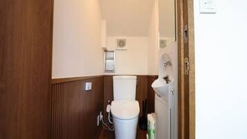 A small, narrow bathroom with a toilet, a sink, and a hand dryer.