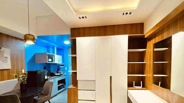 A modern bedroom with a bed, a desk, and a wardrobe.