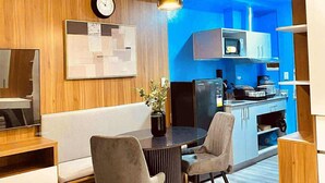 A modern kitchen with blue accent walls, a dining area with a round table and two chairs, and a clock on the wall.