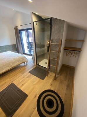 A bedroom with a bed, a glass shower enclosure, a wooden ladder, and a small wooden shelf. - MAURICETTE Chalet—Completely renovated in La Plagne, ideal for families (6 adults/4 children) (La Plagne Tarentaise)