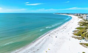 A beach with a long stretch of white sand, clear blue water, and a few buildings in the background. - Charming 2-bedroom house with AC in sunny Sarasota closet to Siesta Key.3711 (Sarasota)