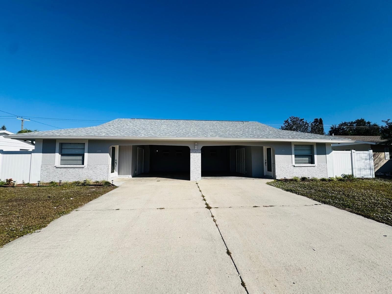 A single-story house with a garage, a driveway, and a clear blue sky.