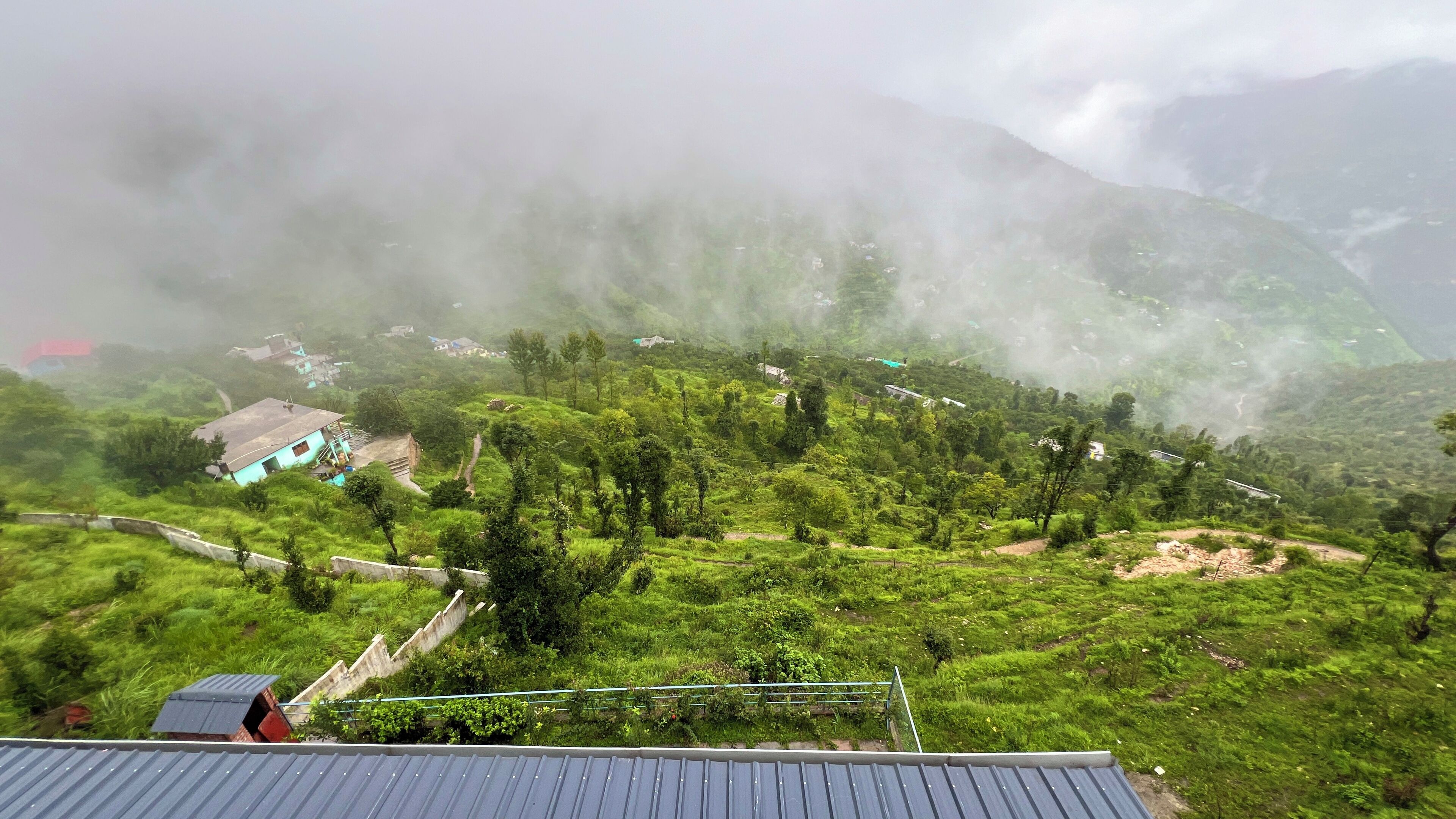 A mountainous landscape with scattered houses and a visible road.