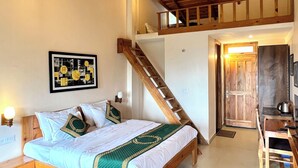 A bedroom with a wooden bed, a staircase, a wooden desk, and a view of the outside.