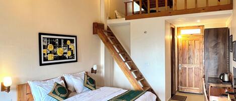 A bedroom with a wooden bed, a staircase, a wooden desk, and a view of the outside.