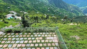 Terraced fields, a fenced area, and scattered buildings in a hilly landscape.