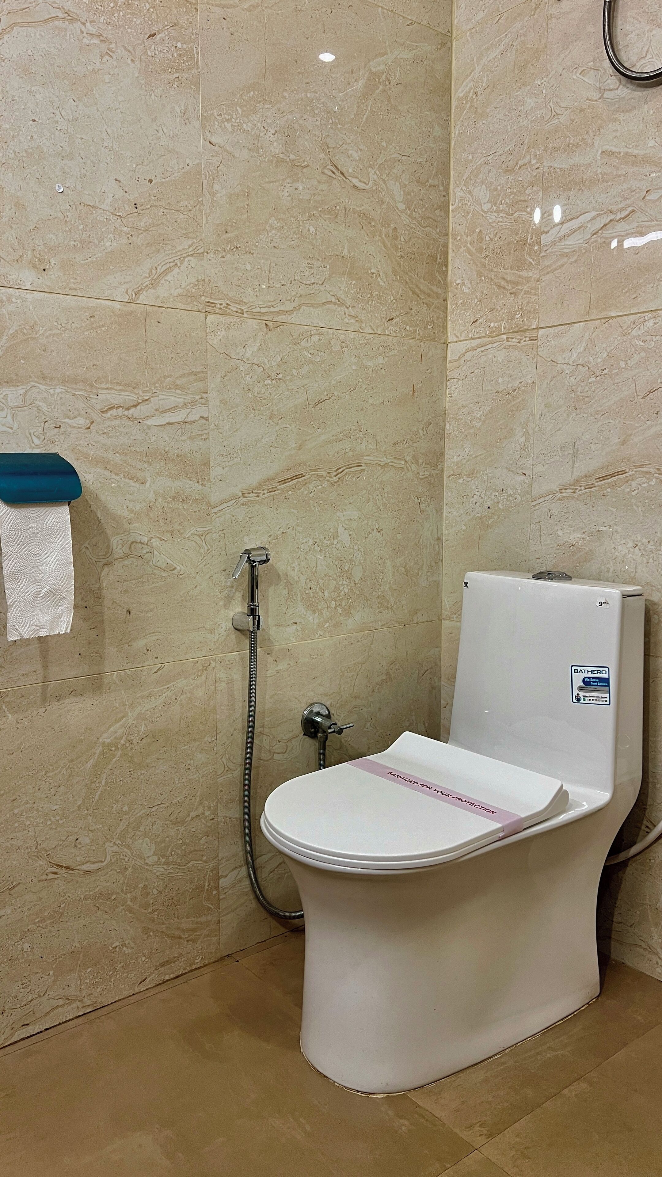 Un baño con inodoro blanco, ducha y una toalla colgada en la pared.