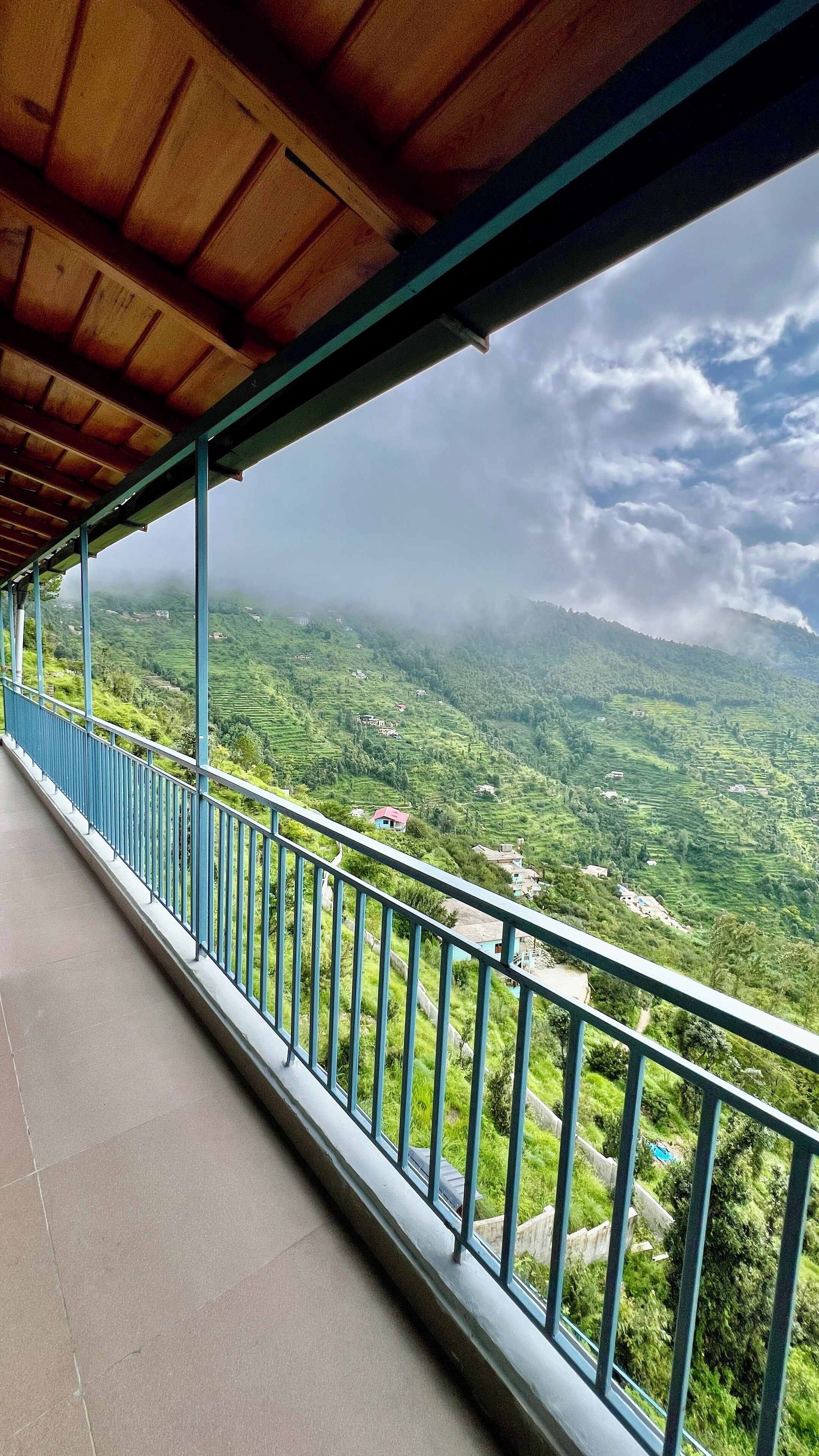 A balcony with a view of terraced fields and houses.