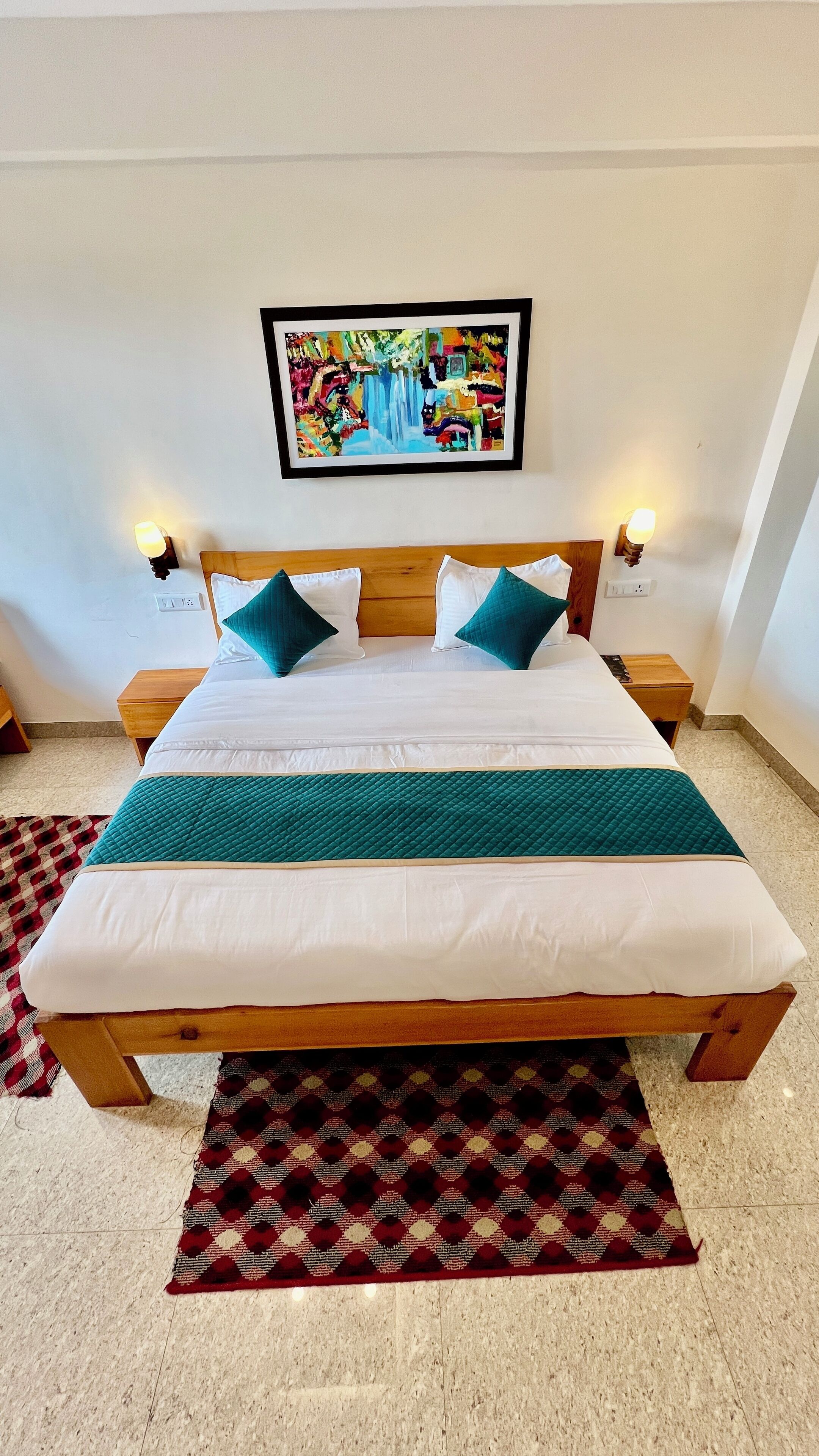 Una cama bien hecha con estructura de madera, ropa blanca y detalles en color aguamarina.
