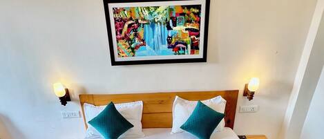 Una cama bien hecha con estructura de madera, ropa blanca y detalles en color aguamarina.