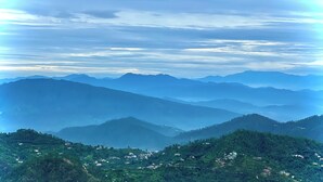 A panoramic view of a mountainous landscape with terraced fields and scattered buildings.