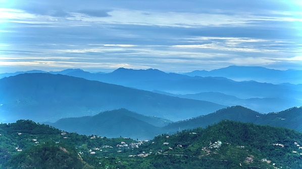 Vista panorámica de un paisaje montañoso con campos en terrazas y edificios dispersos.
