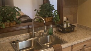 A kitchen with a double sink, wooden cabinets, a dishwasher, and a mirror above the sink. - Spacious 4-bedroom house in welcoming Mobile with AC (Mobile)
