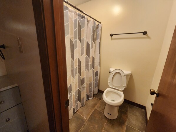 A bathroom with a toilet, a shower curtain, and a towel rack. - Spacious 4-bedroom house in welcoming Mobile with AC (Mobile)