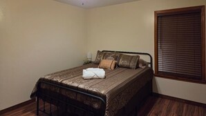 A bedroom with a bed, a ceiling fan, a window with blinds, and a bedside table. - Spacious 4-bedroom house in welcoming Mobile with AC (Mobile)