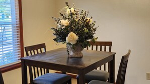 A dining area with a wooden table and four chairs, a chandelier, and a window with blinds. - Spacious 4-bedroom house in welcoming Mobile with AC (Mobile)
