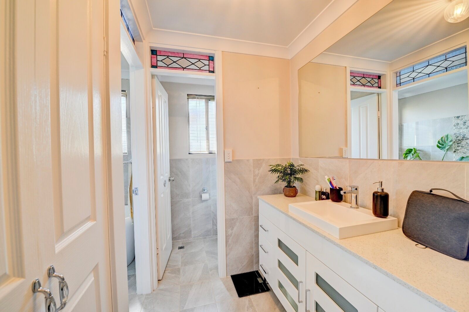 Une salle de bain moderne dotée d’une douche, d’un grand miroir et d’un meuble-lavabo avec un évier et des tiroirs de rangement.