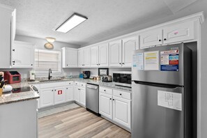 Una cocina moderna con armarios blancos, electrodomésticos de acero inoxidable y encimera de granito.