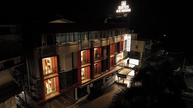 A hotel with multiple floors, balconies, and illuminated rooms. - AS Suites (Kanayannur)
