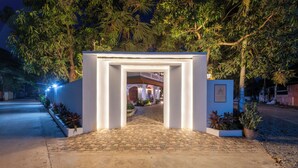 A paved entrance with a white archway leading to a building with a red roof and columns. - The Sears Residence (Siem Reap)