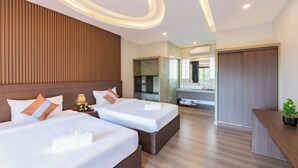 A hotel room with two beds, a wooden headboard, a bedside table with a lamp, a bathroom with a mirror, and a reception desk with a plant. - The Sears Residence (Siem Reap)